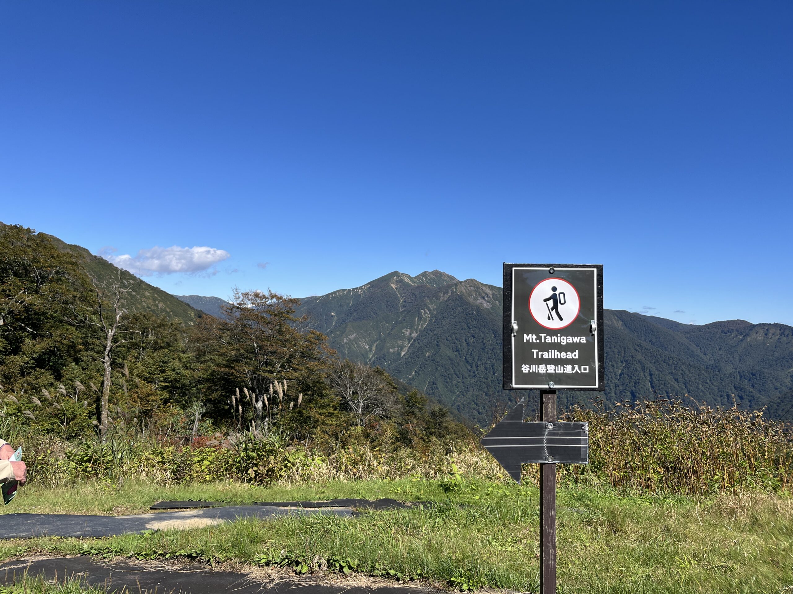 谷川岳の登山道入口を示す案内板と青空